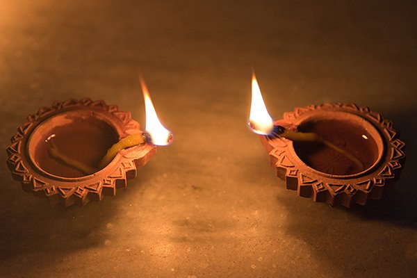 Two burning diyas next to each other